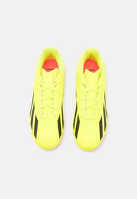 Scarpe da ginnastica gialle con strisce nere, superficie liscia, punta arrotondata, design con lacci e interno rosa a contrasto.