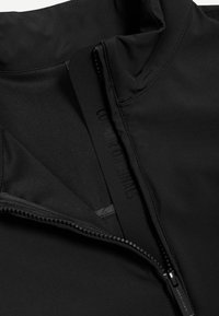 Czarna kurtka z częściowo rozpiętym zamkiem, ukazującym wewnętrzny materiał i wytłoczonym nazwą marki na wewnętrznej klapce.