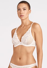 Soutien-gorge blanc en tissu transparent avec des détails en dentelle florale, présentant une forme triangle et des bords festonnés sur les bretelles et la bande.
