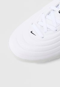 Άσπρο αθλητικό παπούτσι με υφασμένη επιφάνεια, κυματιστό σχέδιο και μαύρο λογότυπο Nike. Διαθέτει λευκά κορδόνια και ελαφριά, λαστιχένια σόλα.