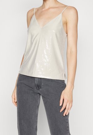 Haut argenté sans manches avec un décolleté en V et des bretelles fines. Tissu texturé avec des sequins, coupe légèrement ample et ourlet droit. Associé à un jean gris.