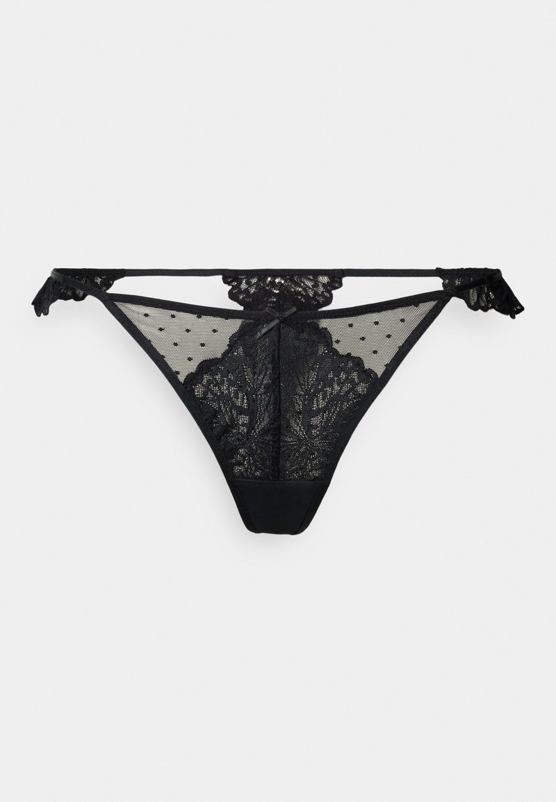 String noir avec des panneaux en dentelle florale et en maille à pois, avec des bords en dents de scie et de délicates nœuds sur les côtés. Doublure intérieure lisse.