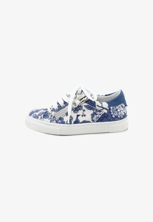Zapatilla deportiva baja con suela blanca, estampado floral azul y blanco, cordones blancos y cremallera lateral sobre fondo blanco.