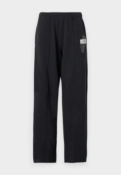 Svarta sportbyxor i mjukt tyg, med elastisk midja, två sidofickor och en liten logopatch på vänster lår.