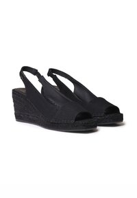 Sandales compensées noires en tissu avec orteils ouverts, brides à enroulement et accents en jute tissé sur le talon. Texture lisse, design minimaliste.