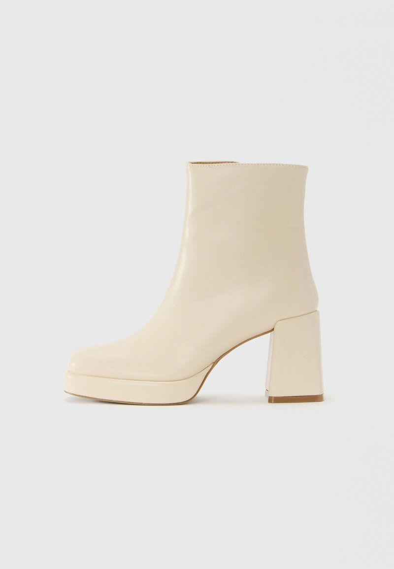 Botte chelsea en cuir beige avec un talon bloc et une semelle à plateforme, finition lisse et pointe légèrement carrée, tournée vers la gauche sur un fond blanc.