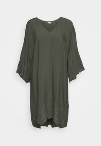 Olivgrüne Tunika mit V-Ausschnitt, dreiviertel Ärmeln und dekorativer Spitzenverzierung mit Cut-out-Details entlang der Ränder. Glatte Textur.