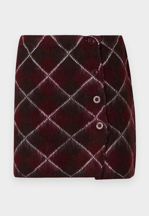 Gebreide rok in bordeauxrood en donkerbruin met een ruitpatroon, voorzien van witte accenten en drie knopen aan de zijkant voor sluiting.