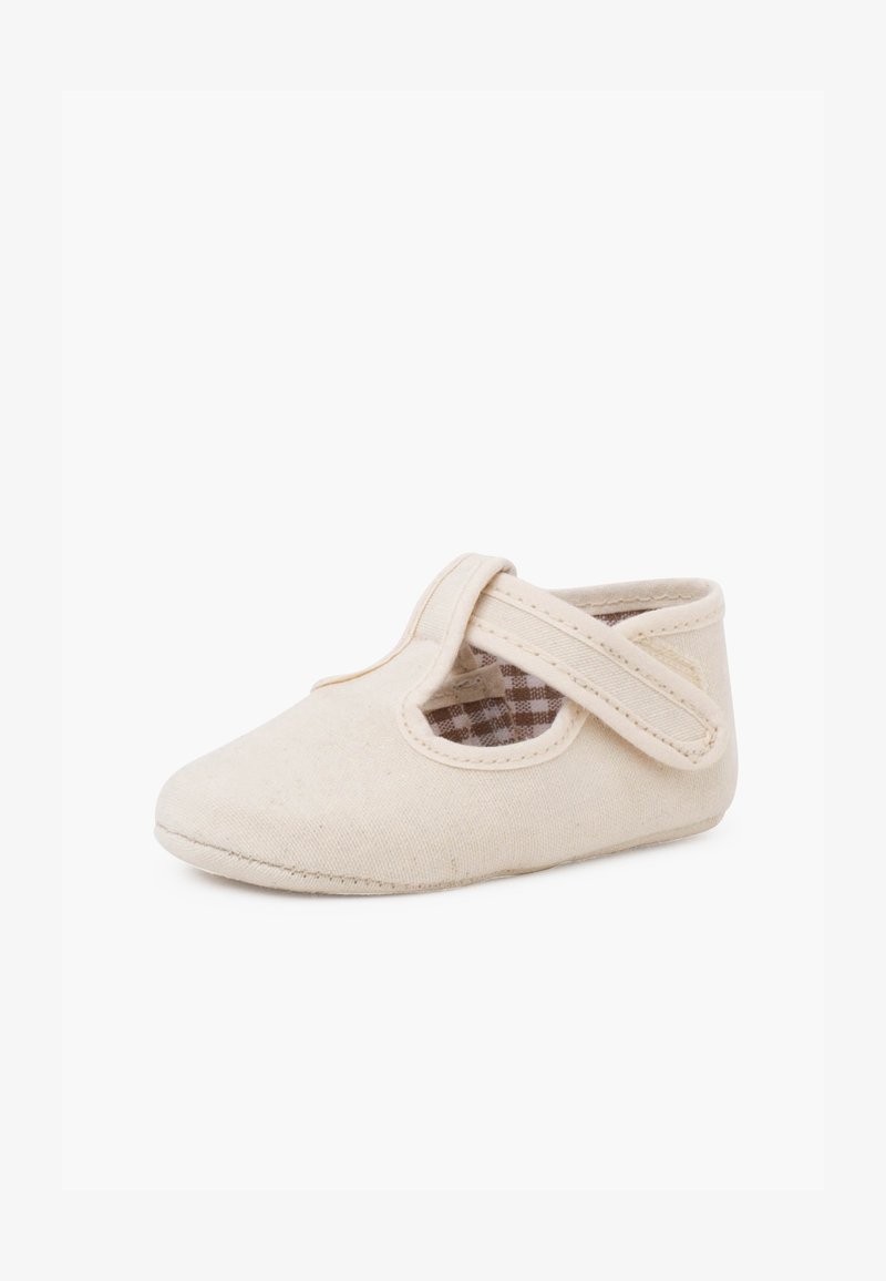 Ballerines en coton beige avec un bout rond, présentant un détail de lanière croisée et une doublure intérieure à carreaux. Texture douce.