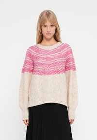 Maglione lavorato a maglia rosa e crema con un motivo testurizzato, colletto rotondo e orlo a coste. Presenta maniche lunghe leggermente a sbuffo.