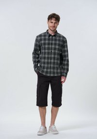 Sort og grå plaid skjorte med knaplukning, parret med knælange sorte cargo shorts med sidelommer og lyse sneakers.