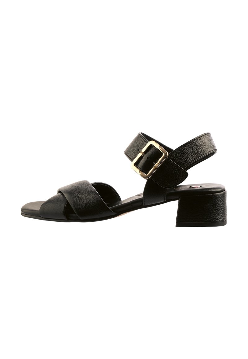 Černé kožené sandály s nízkým blokovým podpatkem, širokými kříženými pásky, nastavitelným páskem kolem kotníku a zlatým detailním sponou.