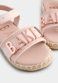 Różowe espadryle na płaskiej podeszwie z plecionym paskiem i metalicznymi literami "BAKE". Charakteryzują się teksturowanym materiałem i plecioną podeszwą z juty.