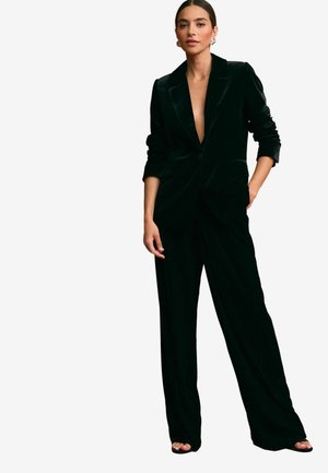 Schwarzer Samtanzug mit einem tiefen V-Ausschnitt-Blazer, einem einzelnen Knopf und weit geschnittenen Hosen. Glatte Textur mit strukturiertem Design.