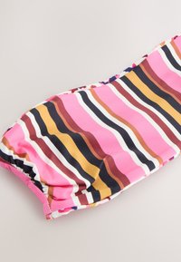 Multifarvet stribet stof med pink, brune og hvide linjer i forskellige bredder. Glat tekstur, samlet kant og buet form.