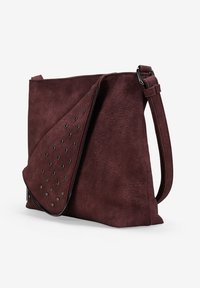 Bolso de faux cuero burdeos con superficie texturizada y tapa doblada con tachuelas negras, correa ajustable y cierre de cremallera.