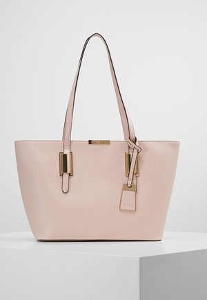 Light pink leather tote bag with two thin shoulder straps, gold rectangular hardware details, and a hanging tag with brand name.