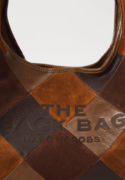 Ruskea patchwork-laukku, jossa on mokka- ja nahkatekstuureja, pyöreä yläosa ja kohokuvioitu teksti "THE SACK BAG MARC JACOBS."