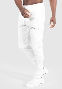 Hvide sweatpants med en afslappet pasform, snor i taljen, sidelommer og et sort logo på låret. Sæt på sammen med hvide sneakers.