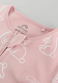 Rosa Baumwollkleidung für Babys mit weißen Hasenmotiven. Mit rundem Ausschnitt und Druckknopfverschluss vorne. Weicher Stoff und leichtes Design.