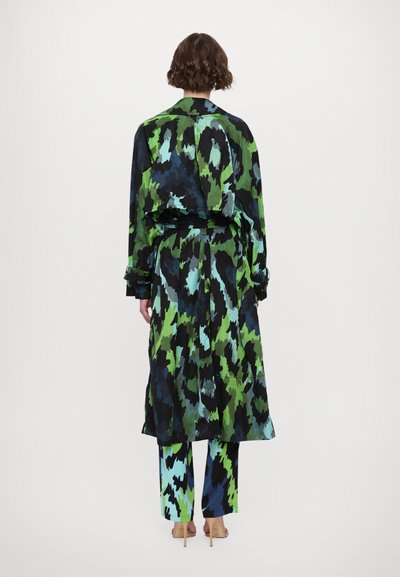 Multicolored outfit featuring a long, patterned coat in greens and blues, paired with matching trousers, both made of lightweight fabric.