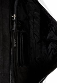 Innenansicht einer schwarzen Stofftasche, die ein Reißverschlussfach und mehrere genähte Taschen zur Organisation kleiner Gegenstände zeigt.