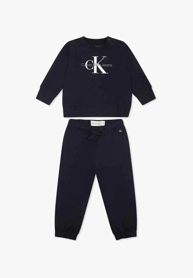 Sudadera azul marino de manga larga con el logo blanco de "Calvin Klein Jeans". Pantalones jogger a juego en azul marino con puños y cinturilla elástica.