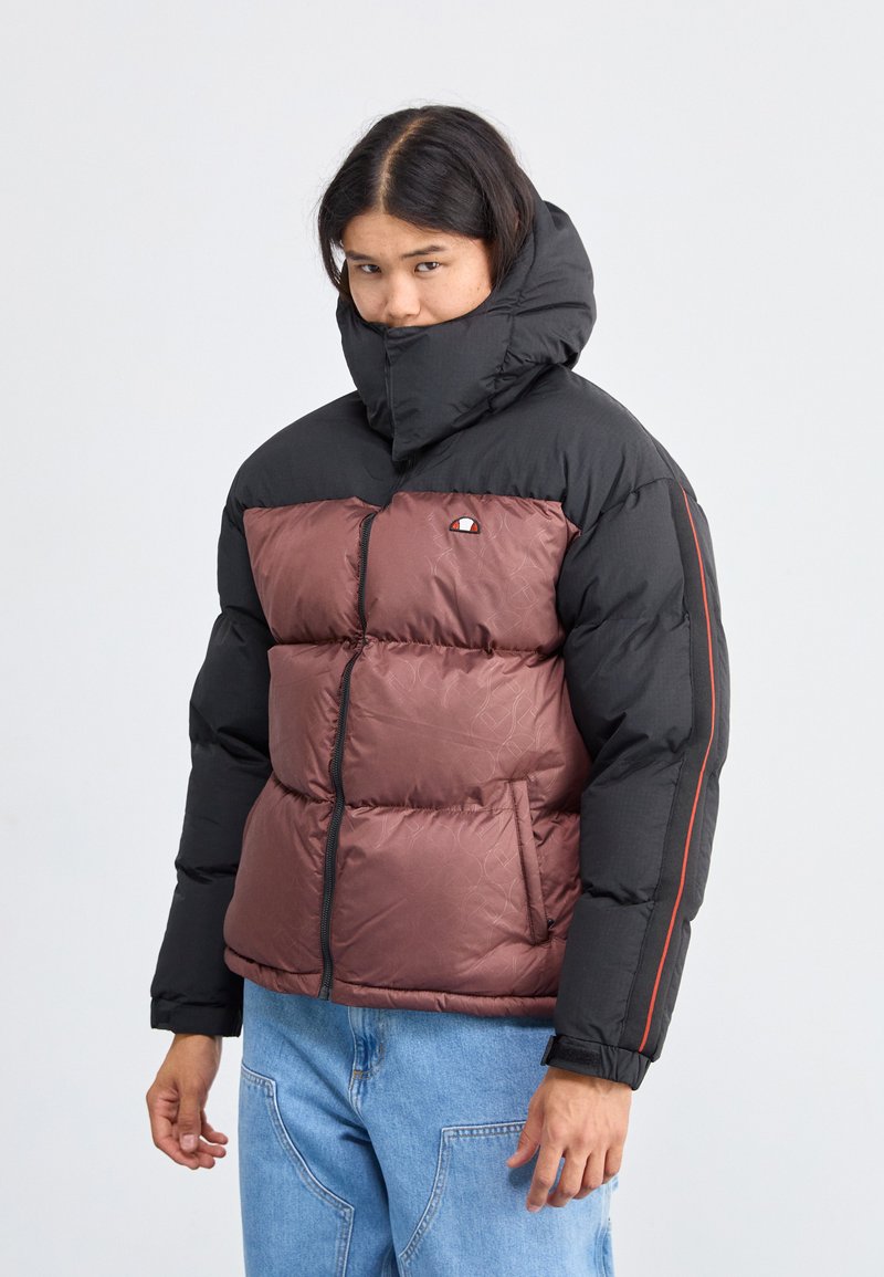 Chaqueta acolchada con capucha y mangas negras, área del pecho en burdeos oscuro con un patrón sutil, cremallera frontal y puños elásticos.