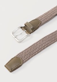 Πλεκτή ζώνη από ταυπ ύφασμα με αποχρώσεις ελιάς στα δερμάτινα άκρα και ασημένια μεταλλική αγκράφα, ακουμπισμένη επίπεδη σε λευκή επιφάνεια.