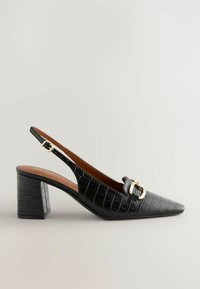Musta krokotiilinjälkeä imitoivat slingback-korkokengät, joissa on terävä vartalo, kultainen soljeyksitys ja paksu lohkokorko. Silkkinen pinta, tyylikäs muotoilu.