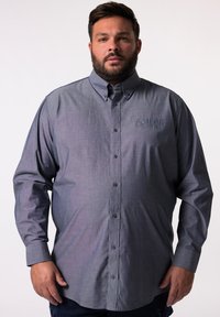 Camisa de botones de manga larga en tejido gris oscuro, con un cuello clásico y detalle bordado de "SAILOR" en el pecho.