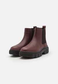 Burgundyskinn Chelsea-boots med svarta elastiska sidopaneler och tjocka svarta gummisulor med ribbad textur.