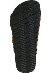 Semelle en caoutchouc noir avec un motif de bande de roulement en zigzag et des trous de drainage. Le côté présente un dessus en cuir marron doux et texturé. Marque Geox visible.