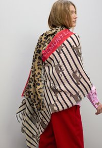 Bufanda multicolor con un diseño de estampado de leopardo y rayas, con una banda de acento rojo llamativa. La tela es ligera y texturizada.