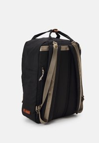 Sac à dos en tissu noir avec des sangles et des accents beiges. Comprend un compartiment zippé et un panneau en maille pour la ventilation. Design compact.