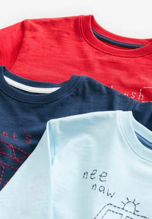 Kolm ümarakaelusega t-särki: punane, mereväesinine ja hele sinine. Mereväesinisel särgil on punane tikand; helesinisel särgil on lihtne graafika ja tekst.