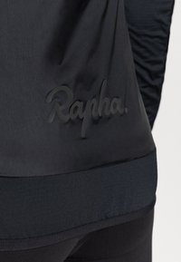 Sort cykeljakke med et glat stof og en let glans, teksturerede detaljer og et prægede "Rapha." logo på den nederste del af ryggen.