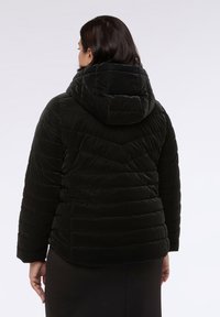 Černá péřová bunda s kapucí, s prošívanými chevronovými vzory, měkkou texturou a lehce zkráceným střihem.