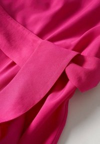 Tissu fuchsia au toucher lisse, avec une large bande et un détail de nœud sur le côté. Le design est simple et él égant.