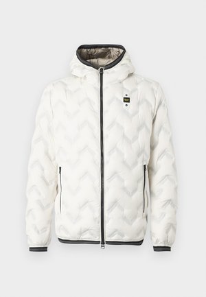 Jachetă puf albă cu glugă, având un model quiltat în zigzag, fermoar negru și manșete cu dungi albe. Design ușor și izolat.