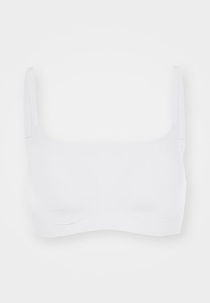 Hvit sømløs bralette med tynne justerbare stropper, myk tekstur og et enkelt, rent design. Ingen polstring eller bøyle.
