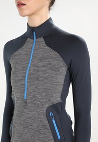 Szary i granatowy długi rękaw sweter z półzamkiem, teksturowany materiał, kontrastowy niebieski zamek błyskawiczny oraz boczne kieszenie z zamknięciem na zamek.