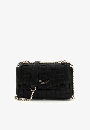 Sac à main matelassé noir Guess avec bandoulière chaîne, fermeture à rabat, et logo en métal argenté "GUESS EST 1981" sur le devant.
