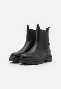 Svart läder Chelsea-boots med elastiska sidopaneler, slät yta, rund tå och en tjock, robust sula för ökad hållbarhet.