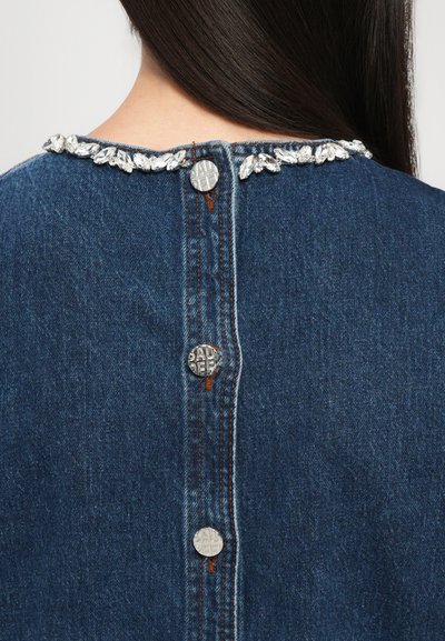 Îmbrăcăminte din denim cu un decolteu rotund decorat cu pietre prețioase transparente, cinci nasturi metalici pe spate și o textură din țesătură albastră.