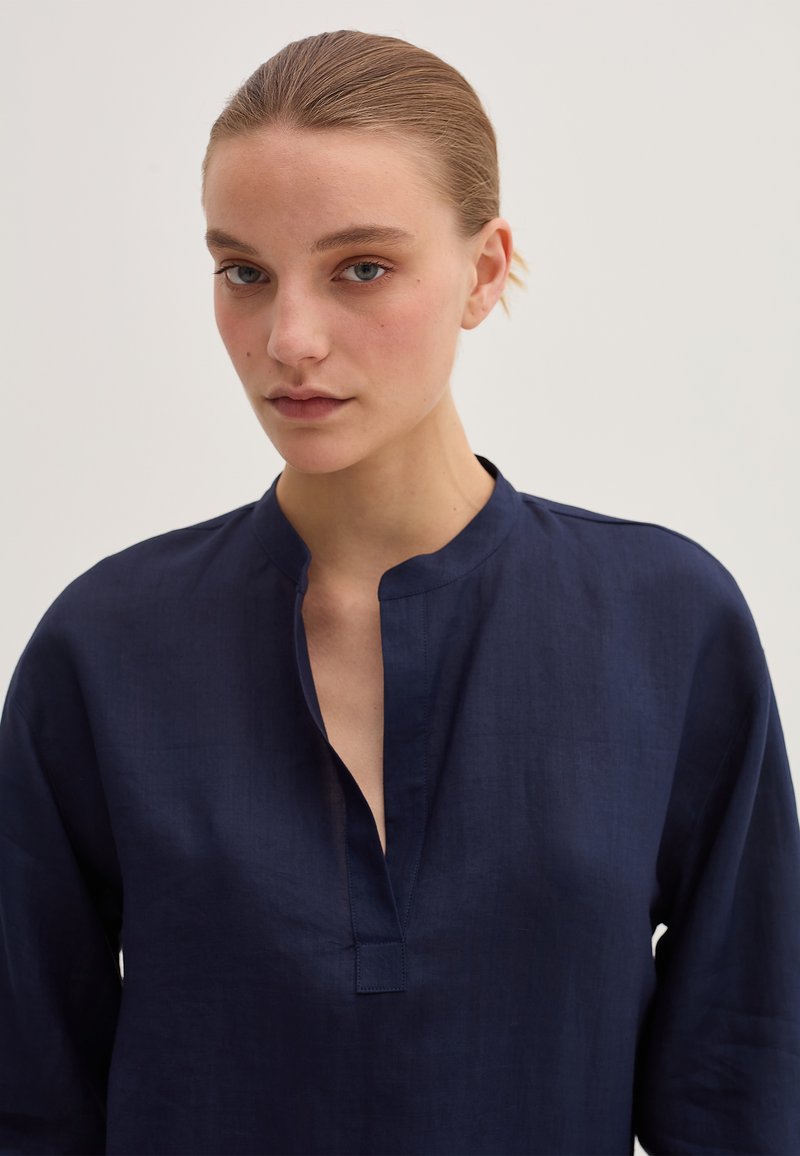 Camicia in lino blu navy con colletto alla cinese, patta senza bottoni e maniche lunghe, caratterizzata da una vestibilità comoda e una texture liscia.