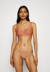 Light brown wireless bra with wide straps and v-neck design, paired with matching sheer bikini briefs. Smooth fabric, minimalist style.