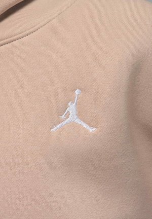 Beżowa bluza z teksturowanej tkaniny, z białym haftowanym logo Jumpman z przodu. Klasyczny krój z okrągłym dekoltem.