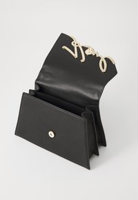 Czarna skórzana torebka na ramię z złotą metalową klamrą z logo. Posiada składany projekt oraz wiele przegrody do uporządkowania rzeczy.