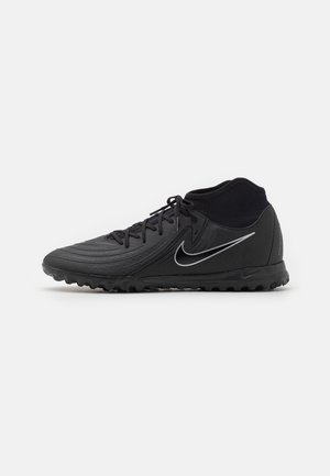 Chaussure de football Nike noire pour terrain synthétique avec lacets, col haut à la cheville, semelle texturée et logo swoosh blanc sur le côté.